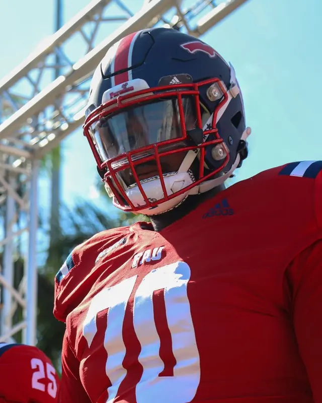 Malcolm in a red Florida Atlantic jersey, number 70, walking out with teammates